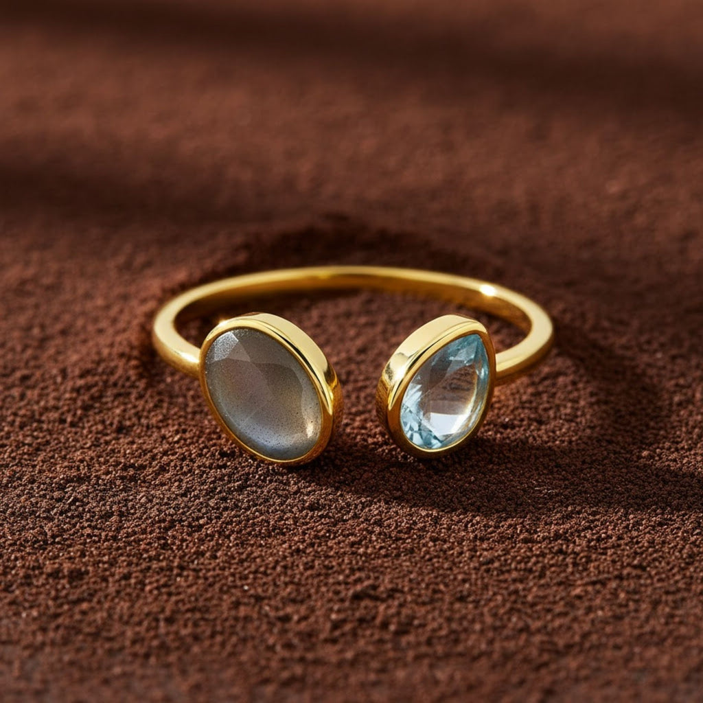 Gold ring with two gemstones on a brown textured background